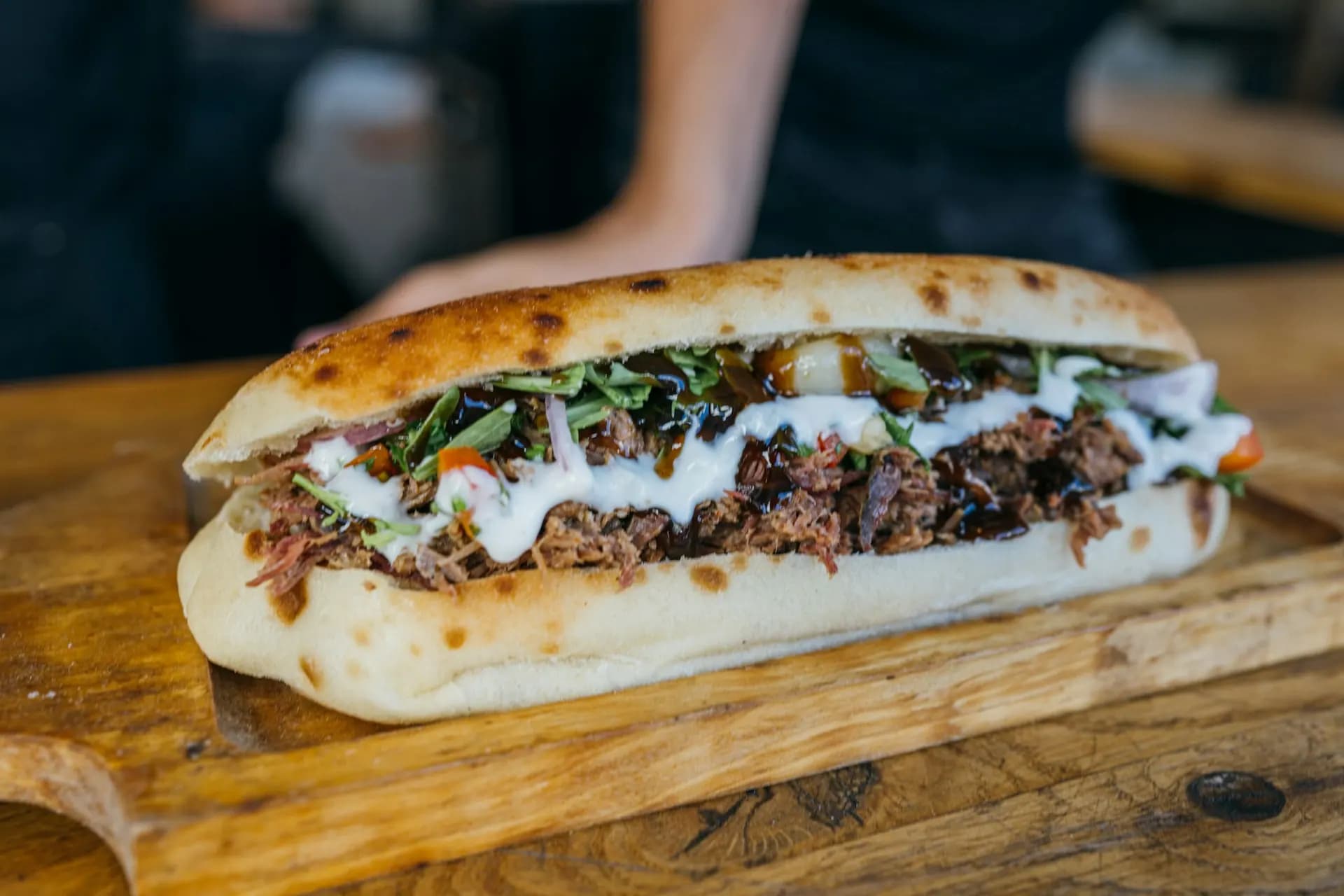 Sandwich kebab garni de viande grillée et de sauce blanche sur une planche